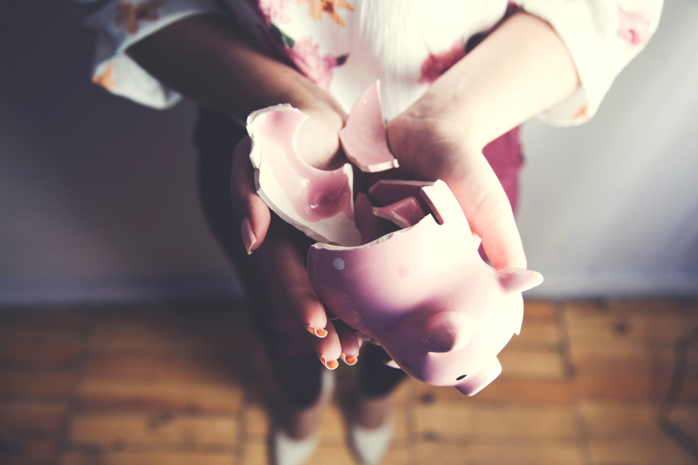 Photo of a woman holding an empty, broken piggy bank. She should have taken our Personal Finance series for transcribers.